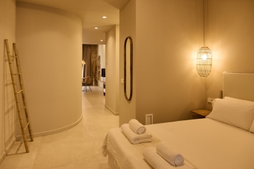 Modern bedroom in Arrels Mercat Valencia apartment with cream bedding, pendant lighting, and hallway view