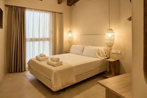 Modern bedroom at Arrels Mercat apartments in Valencia with queen bed, pendant lighting, and city view balcony