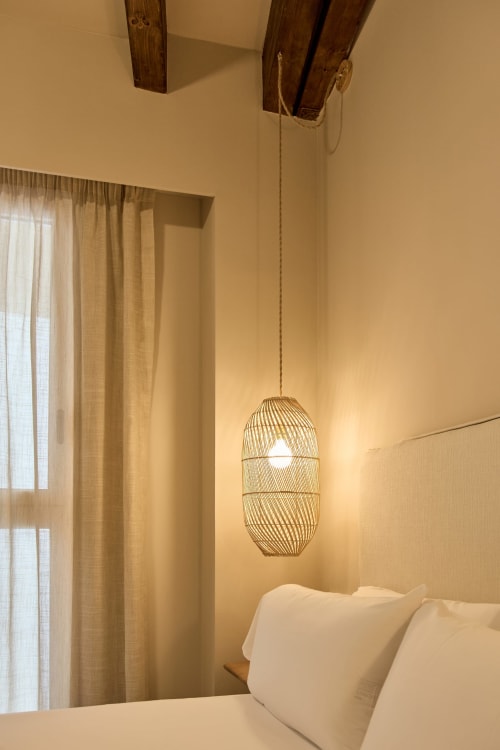 Modern bedroom at Arrels Mercat Valencia apartment with pendant light, white pillows, and sheer curtains