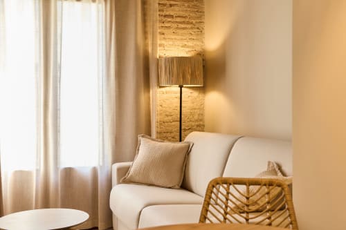 Modern apartment living room at Arrels Mercat Valencia with cream sofa, woven floor lamp, and exposed brick accent wall