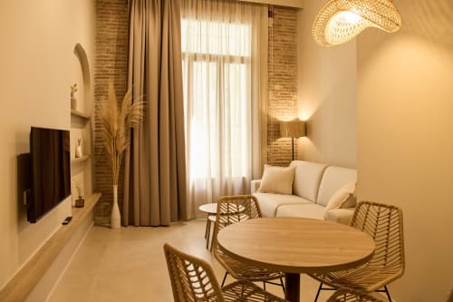 Apartamento moderno en Arrels Mercat Valencia con comedor, sofá crema, sillas tejidas, detalles de ladrillo y luz natural