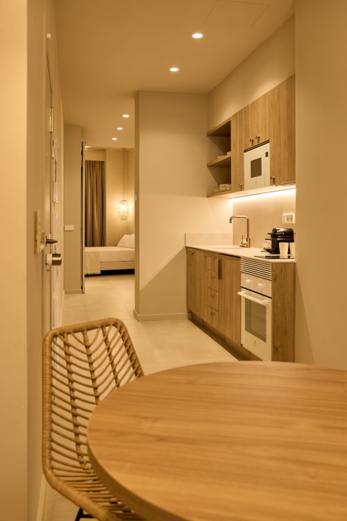 Modern kitchen and dining area in Arrels Mercat apartment, Valencia, with wooden cabinetry and open layout to bedroom