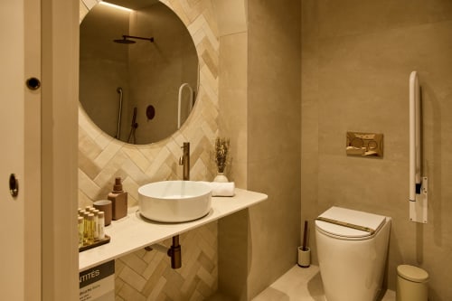 Modern bathroom at Arrels Mercat Valencia apartment with round white sink, circular mirror, herringbone tile backsplash, and