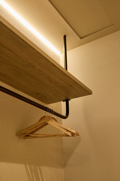 Modern wooden shelf with black metal rail and hanger in Arrels Mercat Valencia apartment, warm ceiling lighting