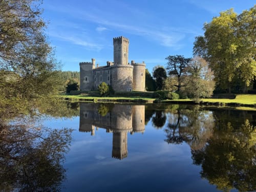 Château médiéval se reflétant dans l'eau calme entouré d'arbres d'automne au domaine de Châlus-Chabrol