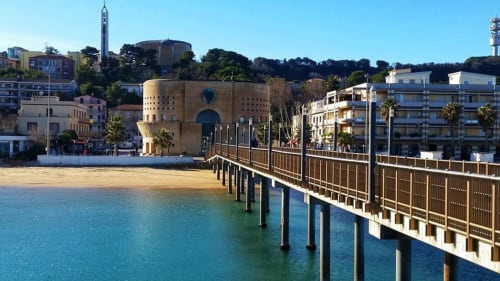 Pescara beachfront with wooden pier, sandy beach, and historic cylindrical tower building near INN property