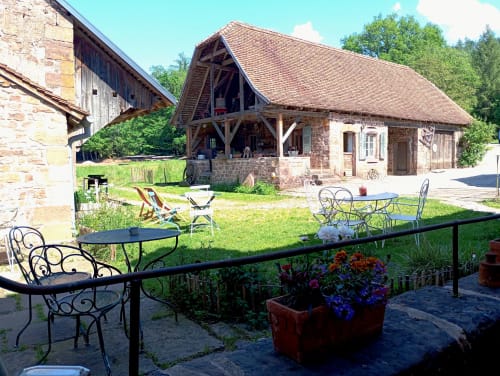 Cour de la maison d'hôtes Paulusmühle à Soucht avec espaces de détente, bâtiments en pierre et terrain verdoyant