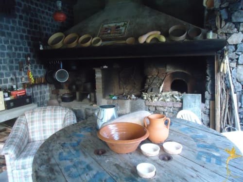 Cozinha rústica da Casa Estrelícia-Dourada Garcês com cerâmica artesanal, lareira e mesa de madeira em São Vicente