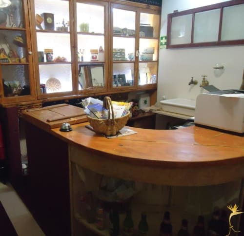 Recepção da Casa Estrelícia-Dourada Garcês BnB em São Vicente com balcão de madeira e vitrinas de vidro