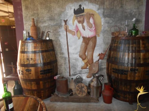 Cenário rústico de taberna com barris de madeira e mural de cowboy na Casa Estrelícia-Dourada Garcês, São Vicente
