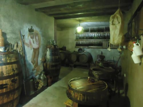 Adega rústica da Casa Estrelícia-Dourada Garcês com barris de madeira, garrafas e decoração tradicional em São Vicente