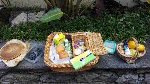 Refeição ao ar livre na A Casa Estrelícia-Dourada Garcês em São Vicente com pão, frutas vermelhas, pastéis e utensílios em vime
