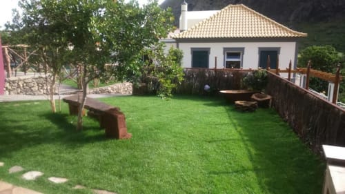 Jardim exuberante com casa branca e telhado em terracota em A Casa Estrelícia-Dourada Garcês em São Vicente