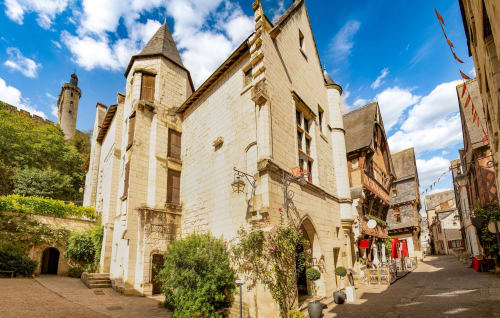 Cour historique en pierre du gîte Maison Romy en France sous un ciel bleu