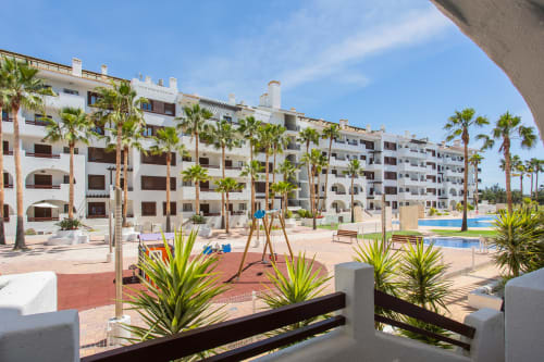 Vista de la piscina del complejo blanco con palmeras en Haus Holiday Homes, San Pedro del Pinatar