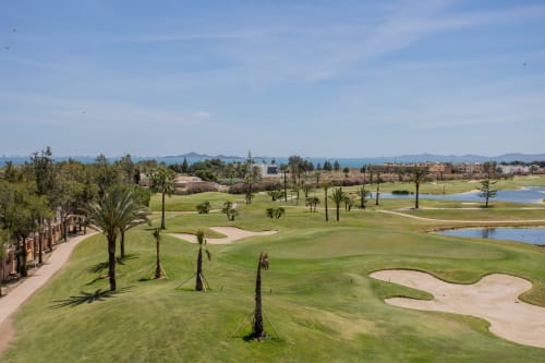 Campo de golf con frondosos fairways, búnkeres, palmeras y lagos en San Pedro del Pinatar, España