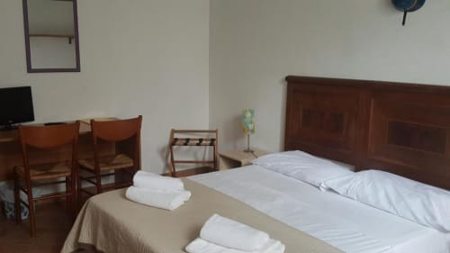 Camera doppia presso Casa di Alfredo B&B a Siena con mobili in legno, cuscini bianchi e vista sul giardino