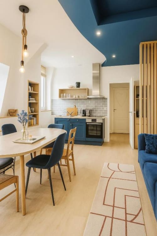 Cuisine-salle à manger moderne de la suite Gabriel à Maunoury Chartres avec mobilier bleu, accents bois et carrelage blanc métro