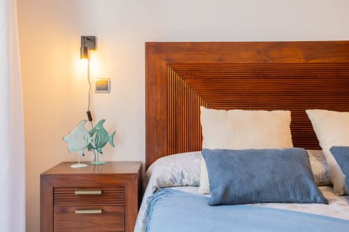 Habitación en apartamento Haus Holiday Homes, San Pedro del Pinatar, con cabecero de madera, almohadas azul rayadas y mesita de noche