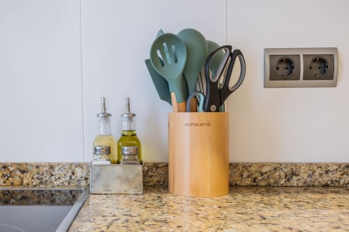 Encimera de cocina con soporte de utensilios de madera, botellas de aceite y toma de corriente en el apartamento Haus Holiday Homes en San Pedro del