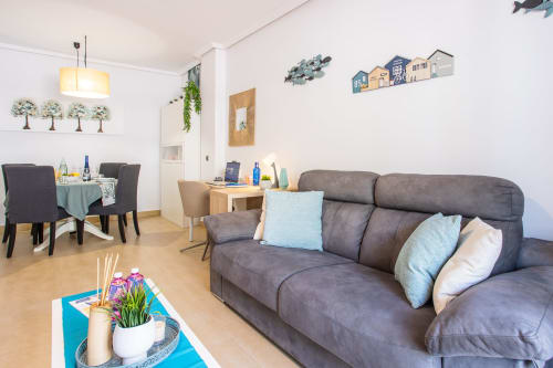 Moderna sala de estar con sofá gris, comedor y decoración costera en San Pedro del Pinatar