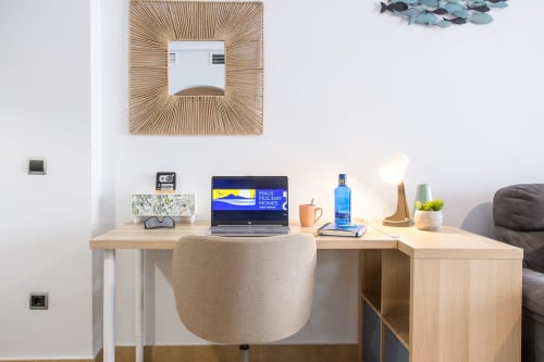 Espacio de trabajo moderno en apartamento Haus Holiday Homes con escritorio de madera, portátil y elementos decorativos en San Pedro del Pinatar