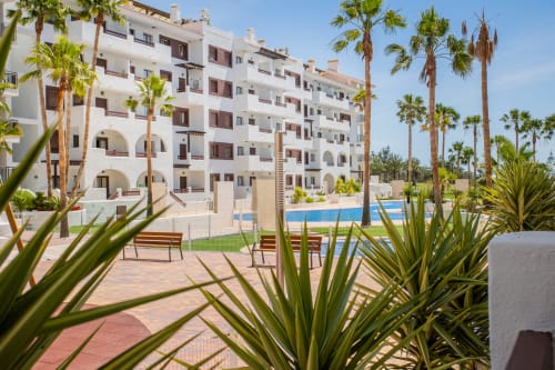 Edificio blanco de apartamentos con palmeras y piscina compartida en Haus Holiday Homes, San Pedro del Pinatar, España