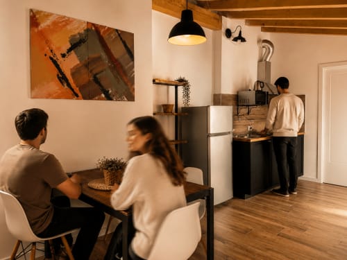 Modernes Loft-Apartment in Bergamo mit offener Küche, Essbereich und Gästen in stilvollem, warmem Ambiente