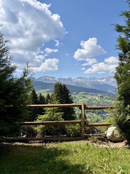 Clôture en bois encadrant les Alpes enneigées et la vallée verdoyante de Demi-Quartier à La Ferme 1828