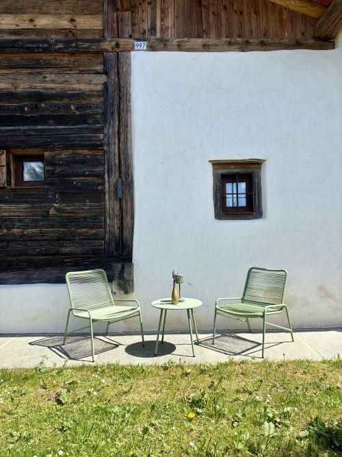 Chaises et table vertes sur la terrasse du gîte La Ferme 1828 à Demi-Quartier, France, avec bâtiment chaulé et poutres en bois
