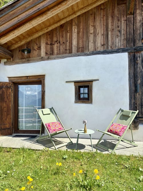 Chambre Janine à La Ferme 1828 avec transats sur la terrasse, vue sur les montagnes, murs blancs et poutres en bois rustique
