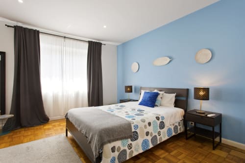 Chambre moderne au 100 Contos Porto avec mur d'accent bleu, lit en bois foncé, literie à motifs et parquets en famille