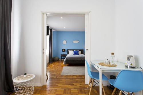 Modern family room at 100 Contos Porto with blue accent wall, bed, work desk with blue chair, and wooden floors