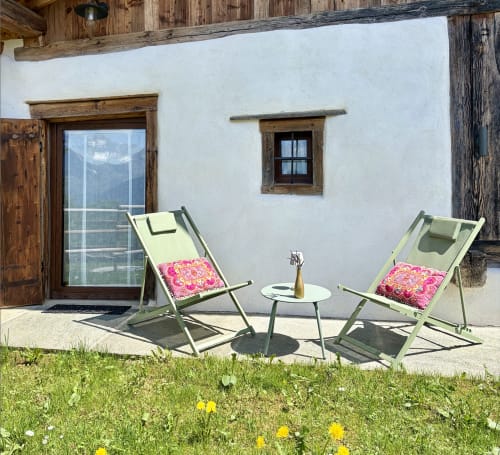 Coin détente de la terrasse à La Ferme 1828 à Demi-Quartier avec deux chaises longues vertes et vue sur les montagnes