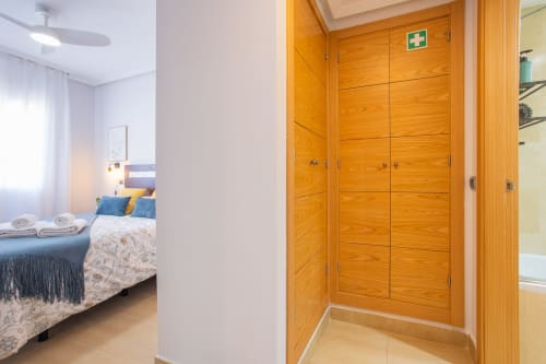 Moderno dormitorio con puertas de armario de madera y baño en suite en el apartamento Haus Holiday Homes de San Pedro del Pinatar