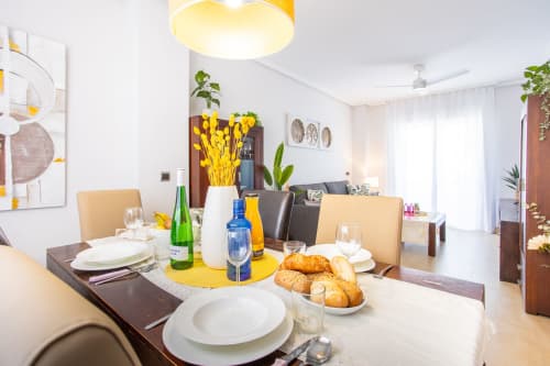 Zona de comedor moderna en apartamento Pura Vida II con mesa servida, pasteles frescos, detalles en amarillo y vista al jardín en San Pedro del