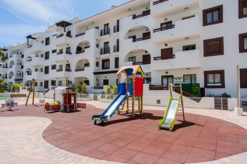 Parque infantil al aire libre con toboganes de colores en Haus Holiday Homes, San Pedro del Pinatar, España, rodeado de edificios blancos
