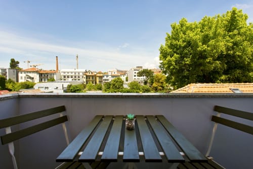 City view from balcony of 100 Contos BnB double room in Porto, with wooden bench and urban skyline