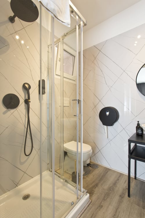 Modern bathroom in Porto's 100 Contos BnB with shower cabin, black fixtures, and wooden flooring