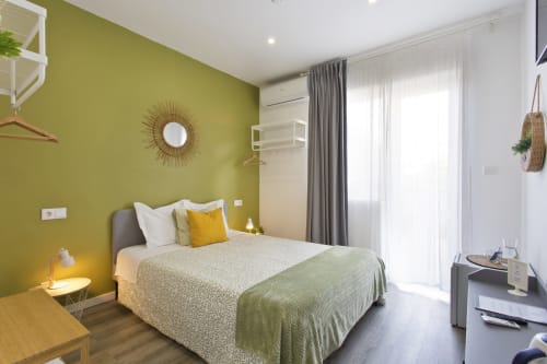 Modern bedroom at 100 Contos Porto with lime green accent wall, queen bed, flat-screen TV, and balcony access to city views.