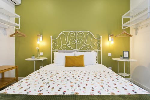 Modern bedroom at 100 Contos B&B Porto with lime green walls, white metal headboard, floral bedding, and brass gold accent