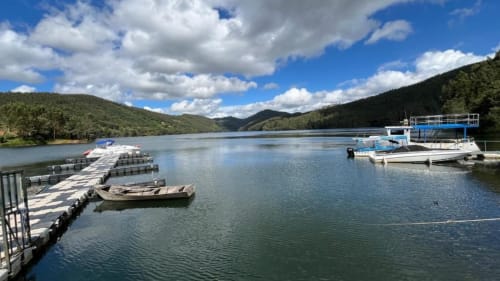 Vista serena do lago com barcos atracados, cais de madeira e colinas florestadas em Quinta da Mata de Baixo, Cágida Portugal