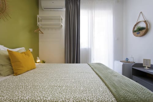 Modern double bedroom with city view at 100 Contos Porto B&B, featuring yellow accent wall, balcony doors, and contemporary