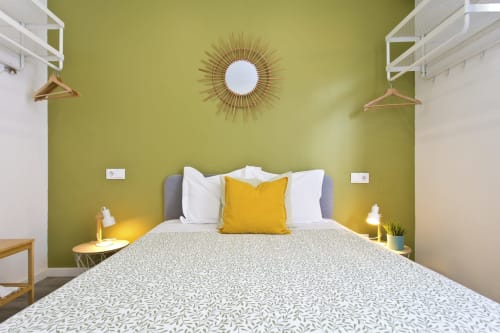 Bright modern bedroom at 100 Contos guesthouse in Porto with olive green walls, yellow sunburst mirror, queen bed with white