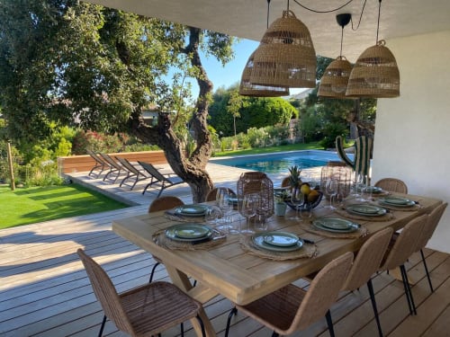 Terrasse de restauration au bord de la piscine de la villa CASA DI SADREA à Lecci avec table dressée, lampes suspendues en osier et piscine bleue