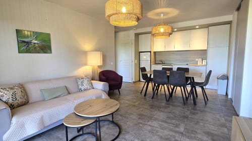 Modern villa living area with seating, dining table, kitchen, pendant lights and nature artwork at Villas Lantana, Lecci