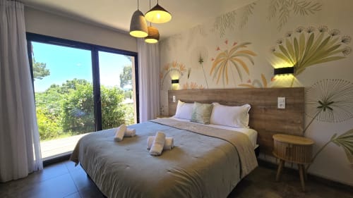 Modern bedroom at Villas Lantana in Lecci with sea view, wooden headboard, pendant lights, and botanical wall art