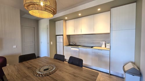 Modern kitchen and dining area in Villa 2 bedrooms at Villas Lantana, Lecci with white cabinetry and wooden table