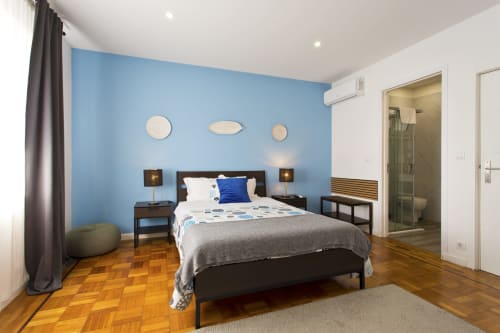 Modern family bedroom at 100 Contos Porto with blue accent wall, dark wood bed, parquet flooring, and en-suite bathroom