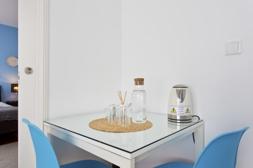 Modern dining table with electric kettle, water bottle, and diffuser in Porto family room with blue chairs